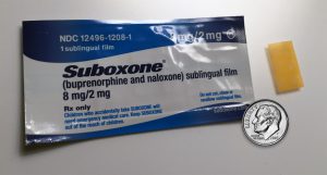 A package of suboxone is shown next to a coin.
