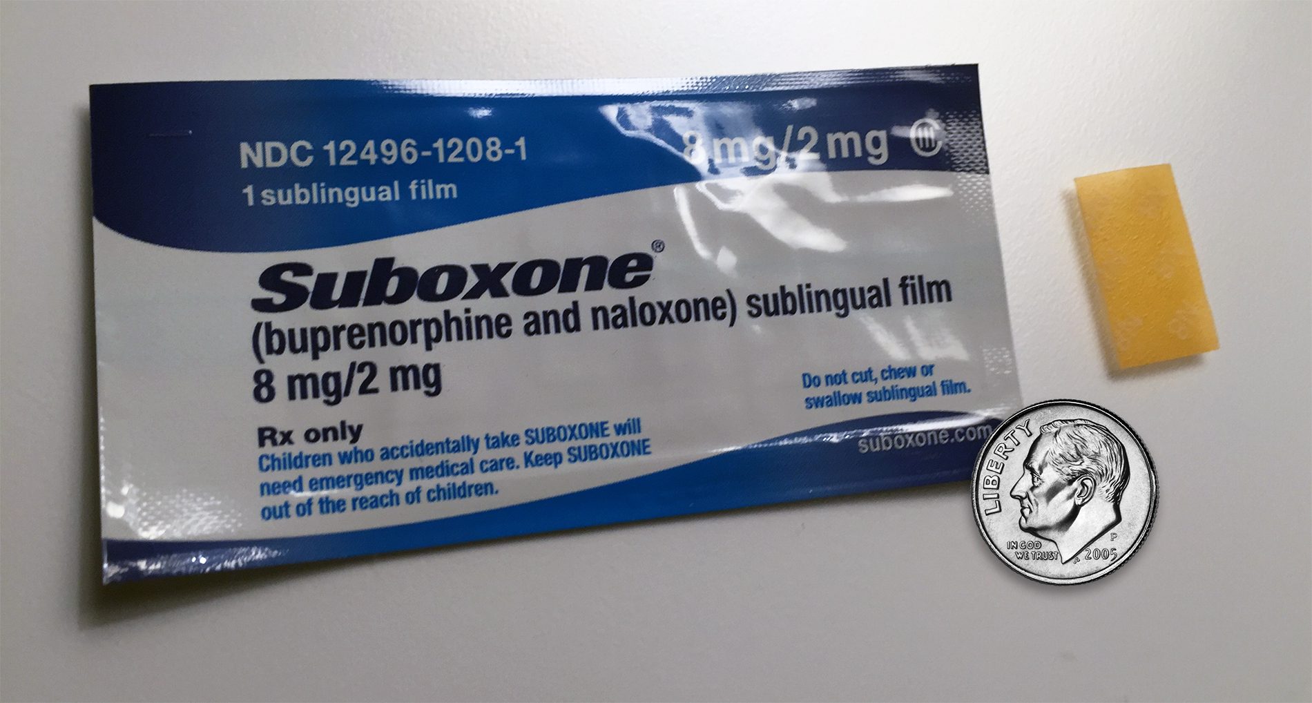 A package of suboxone is shown next to a coin.