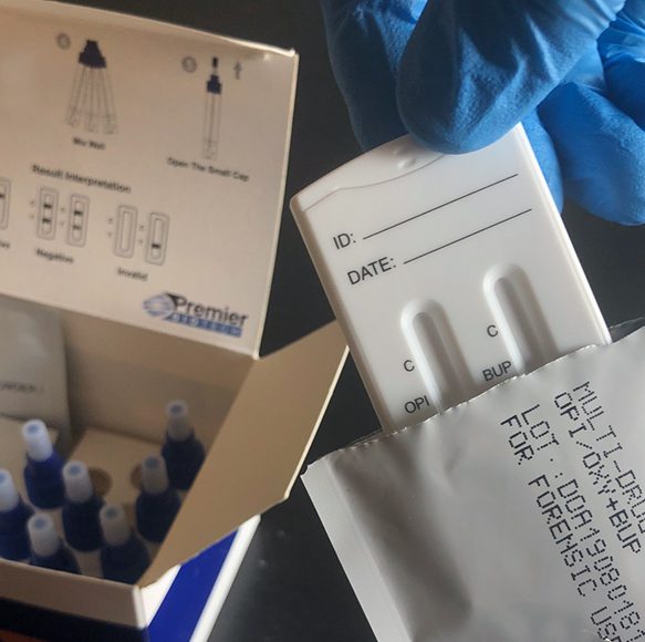 A person holding a box of needles and a blue glove.