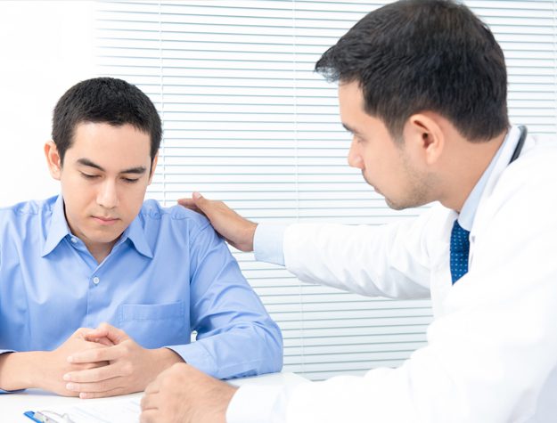 A doctor is showing a patient something on his shoulder.