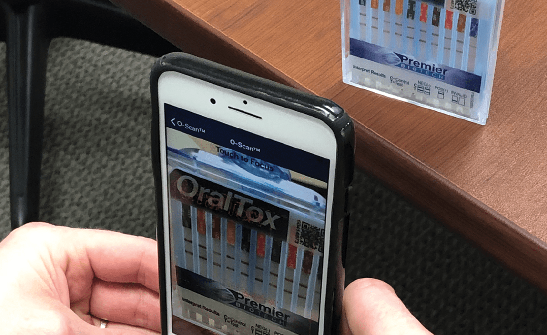A person holding an iphone with the oral-b toothbrush app on it.