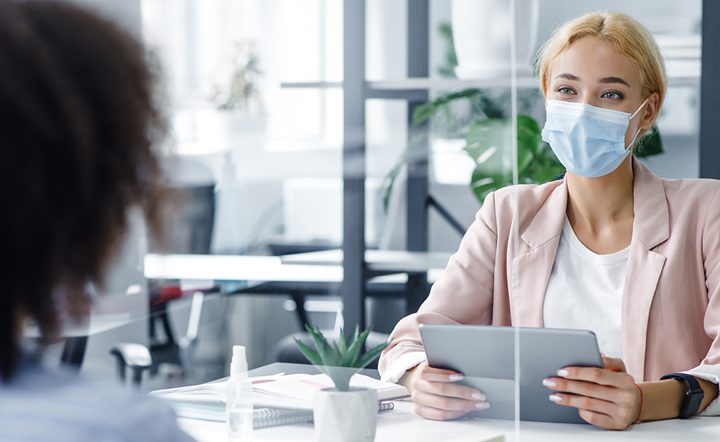 A woman in pink jacket holding a tablet.