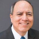 A man in suit and tie smiling for the camera.