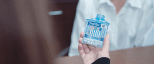 A person holding an oral-b box with tooth brushes in it.