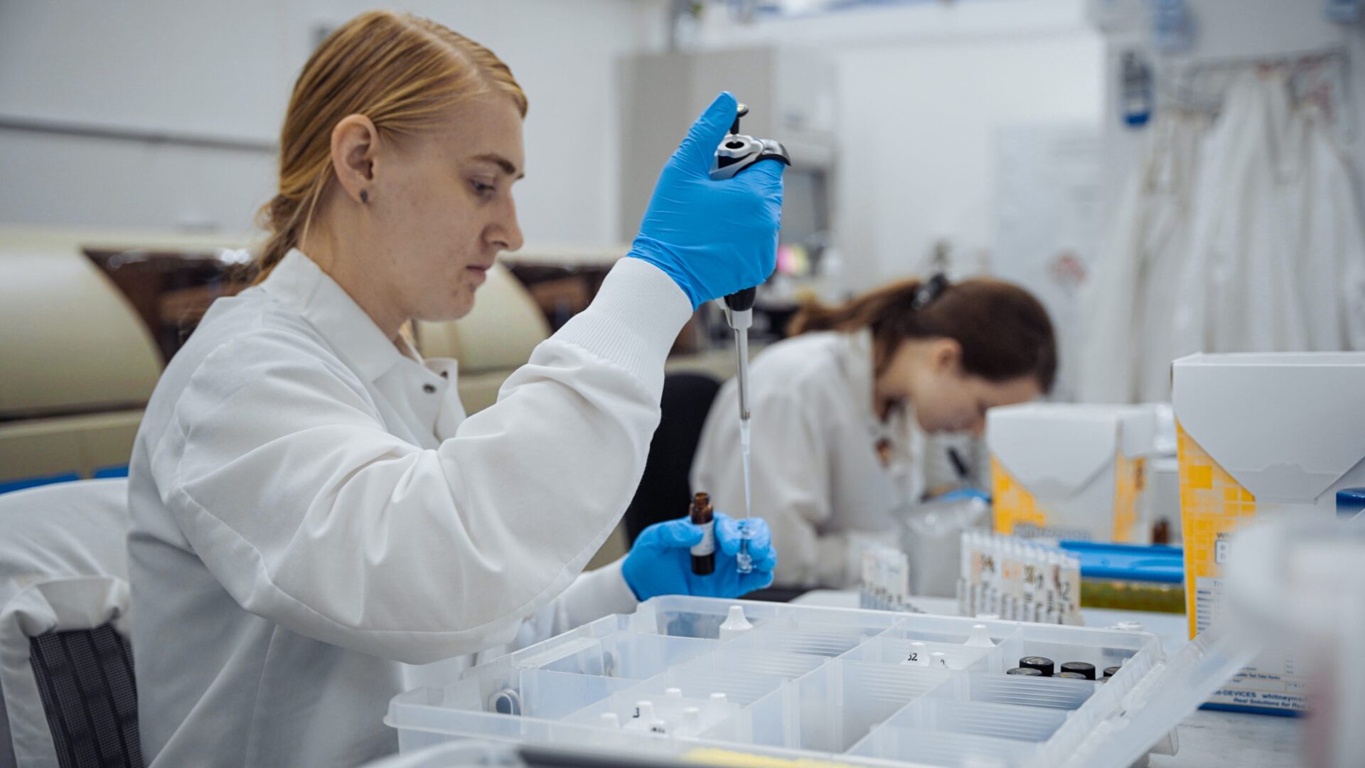 A woman in white lab coat holding a tube of liquid.