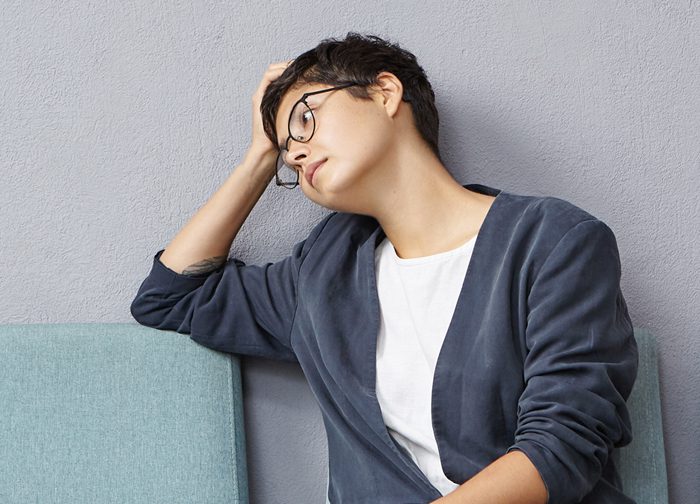 A man with glasses leaning against the wall