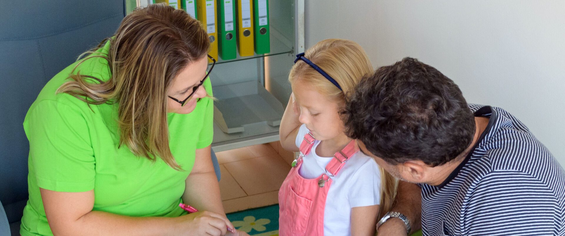 A woman and two children are looking at papers.